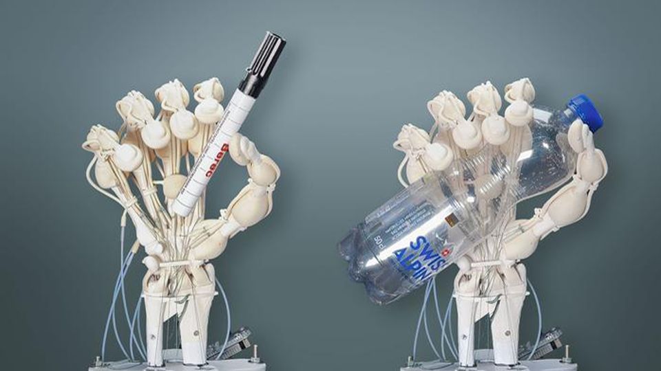 Two robotic hands holding a pen and a water bottle.